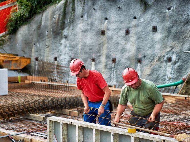 Zwei Arbeiter errichten eine Hausmauer